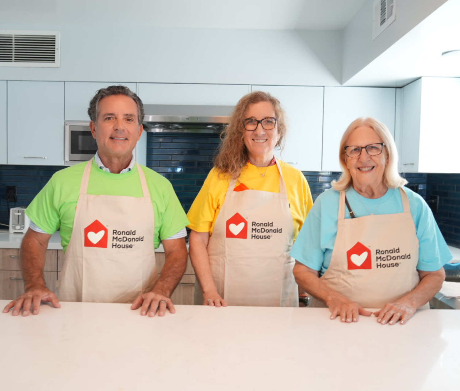 Volunteers in the kitchen, wearing Ronald McDonald House aprons