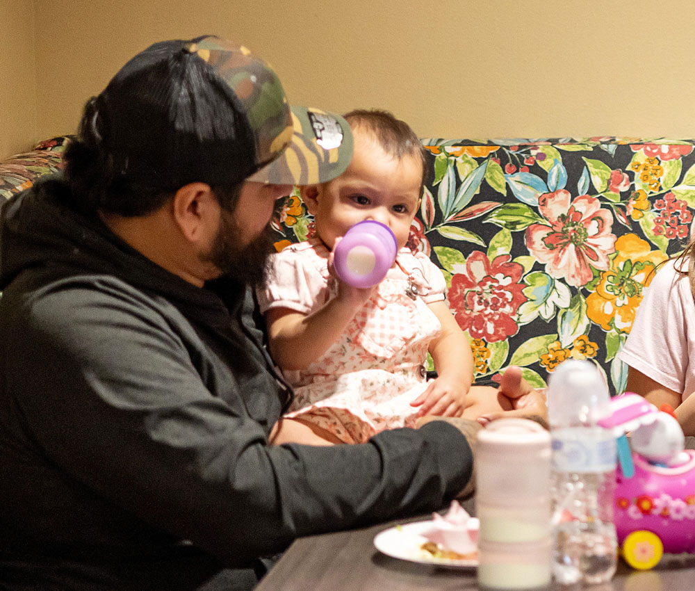 father feeding toddler baby
