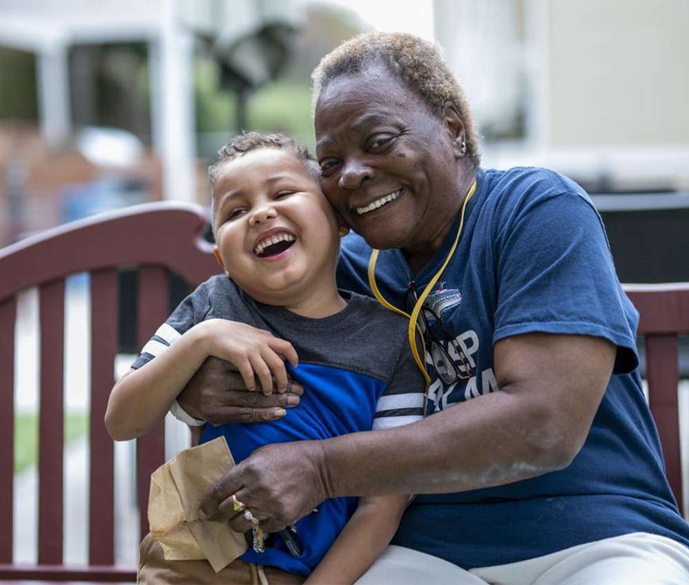elder volunteer hugging young boy