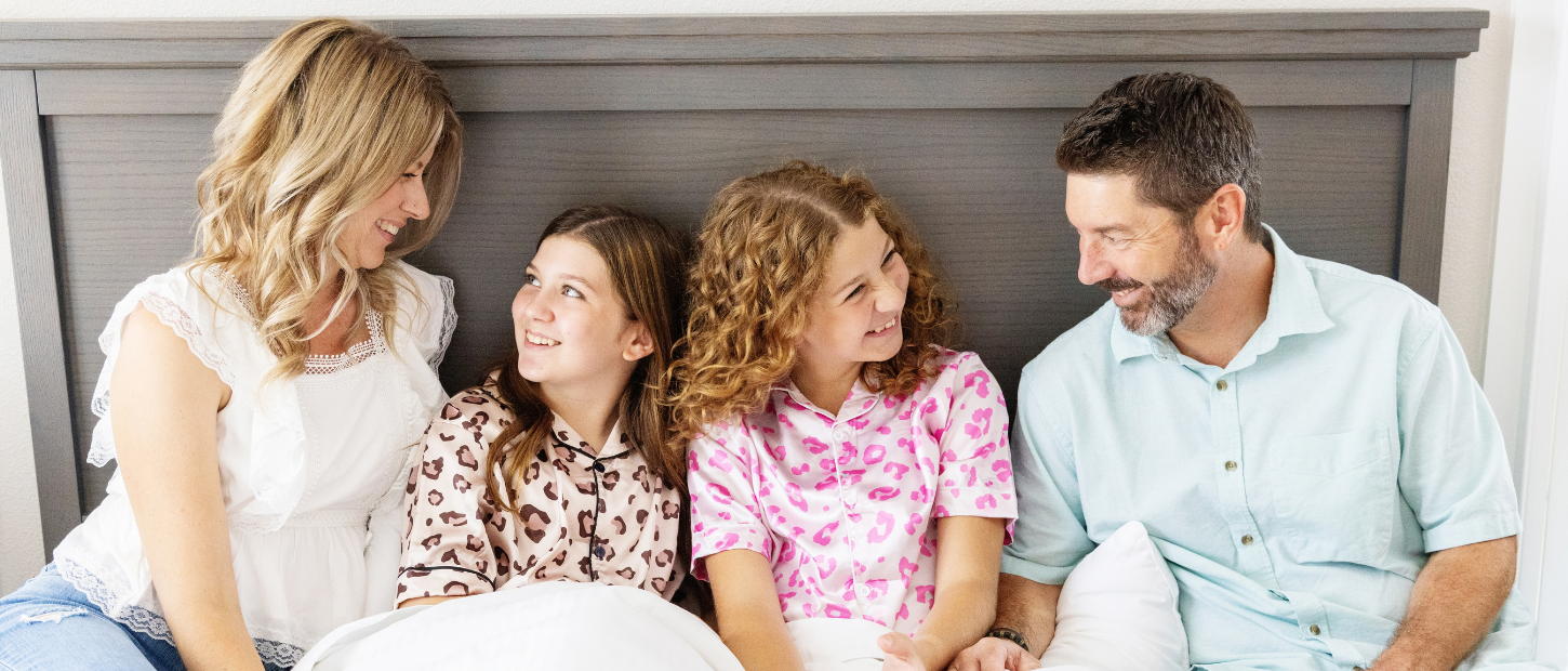 Family sitting together on bed in bedroom