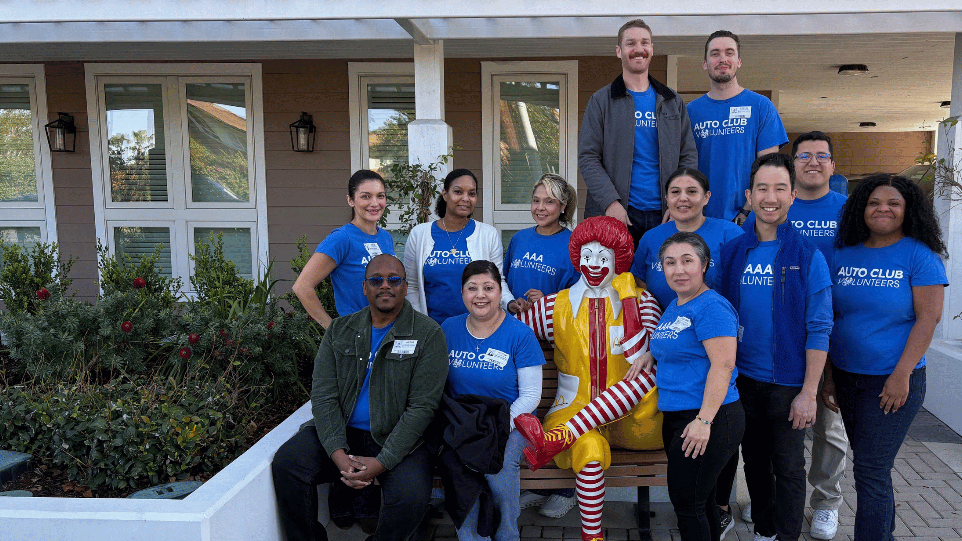 diverse group of volunteers sitting outside with a ronald mcdonald statue