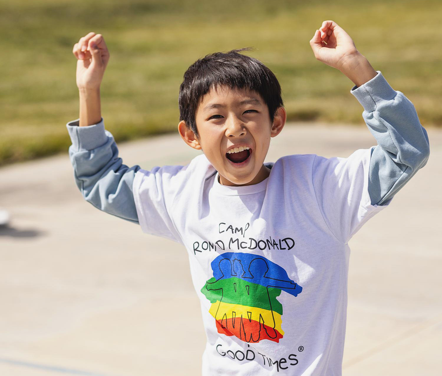 boy in Camp Ronald McDonald t-shirt running and cheering