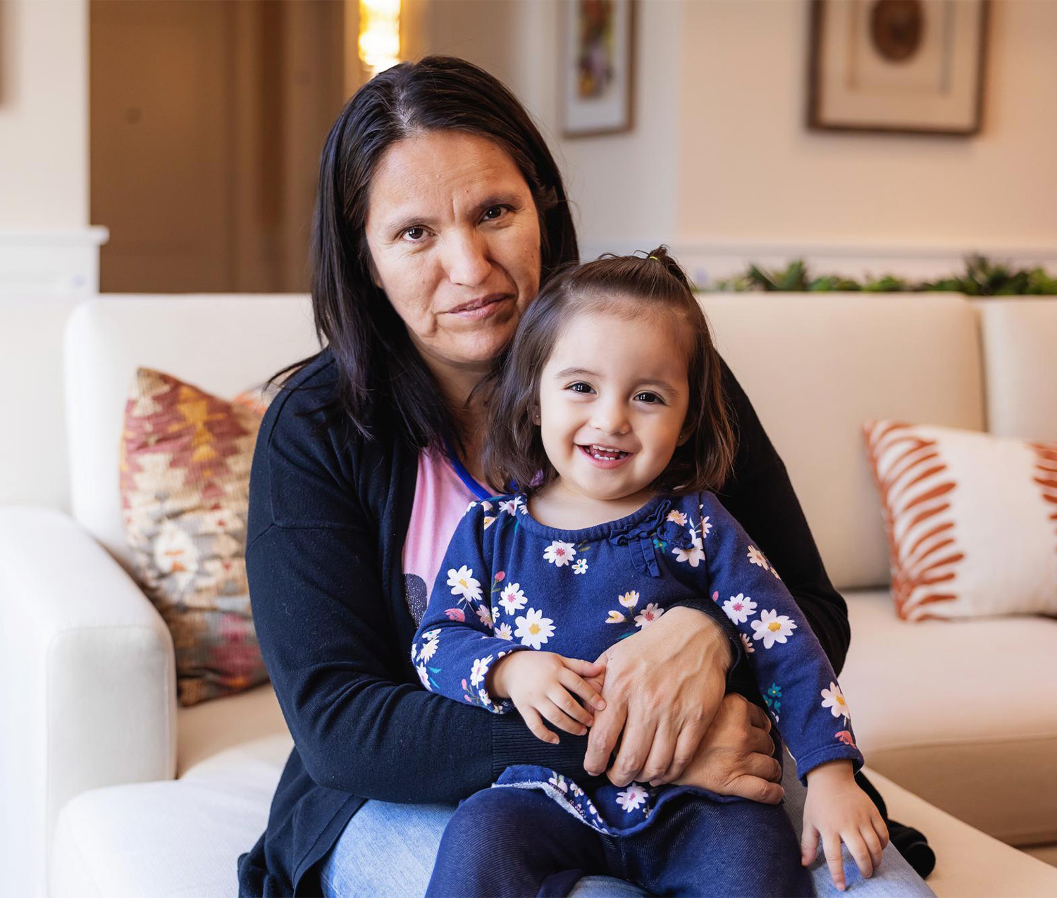 mother holding young girl sitting on coach