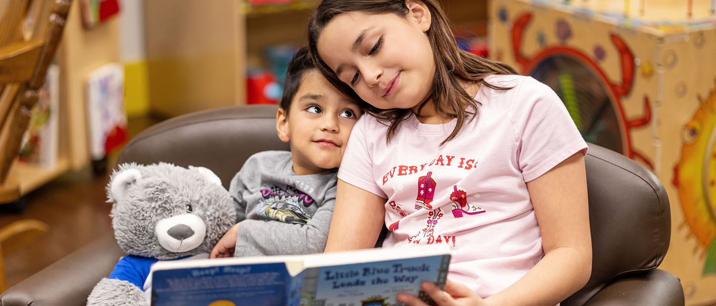 big sister reading story to brother