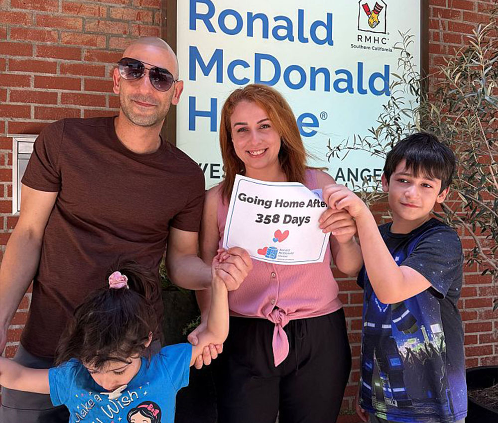 Ariadne's family photo in front of Ronald McDonald House sign